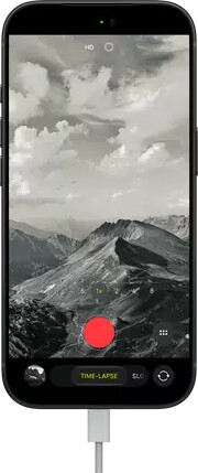 iPhone 18 Pro, front exterior, displaying a mountainous landscape, with the camera mode overlay in Time-Lapse mode, with power cable attached to charging port