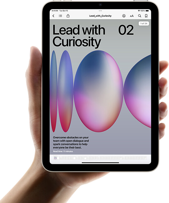 A user holds iPad mini in portrait view in one hand. The screen displays the Books app